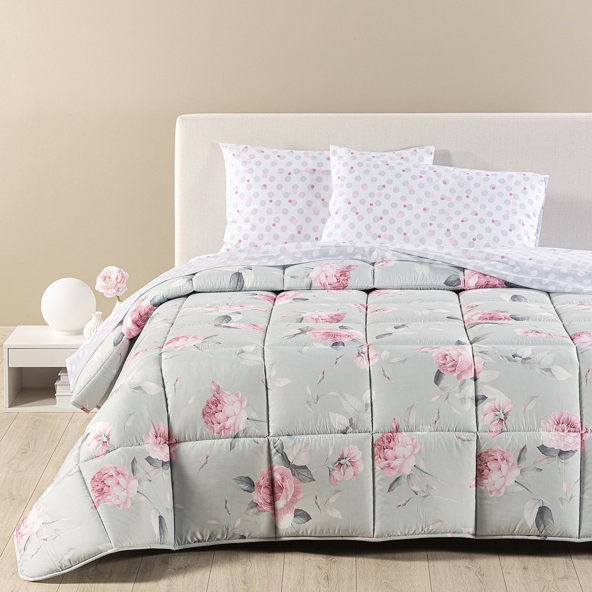 Trapunta invernale matrimoniale Caleffi Bella Rosa sul letto, con grandi rose rosa e foglie grigie su fondo grigio chiaro