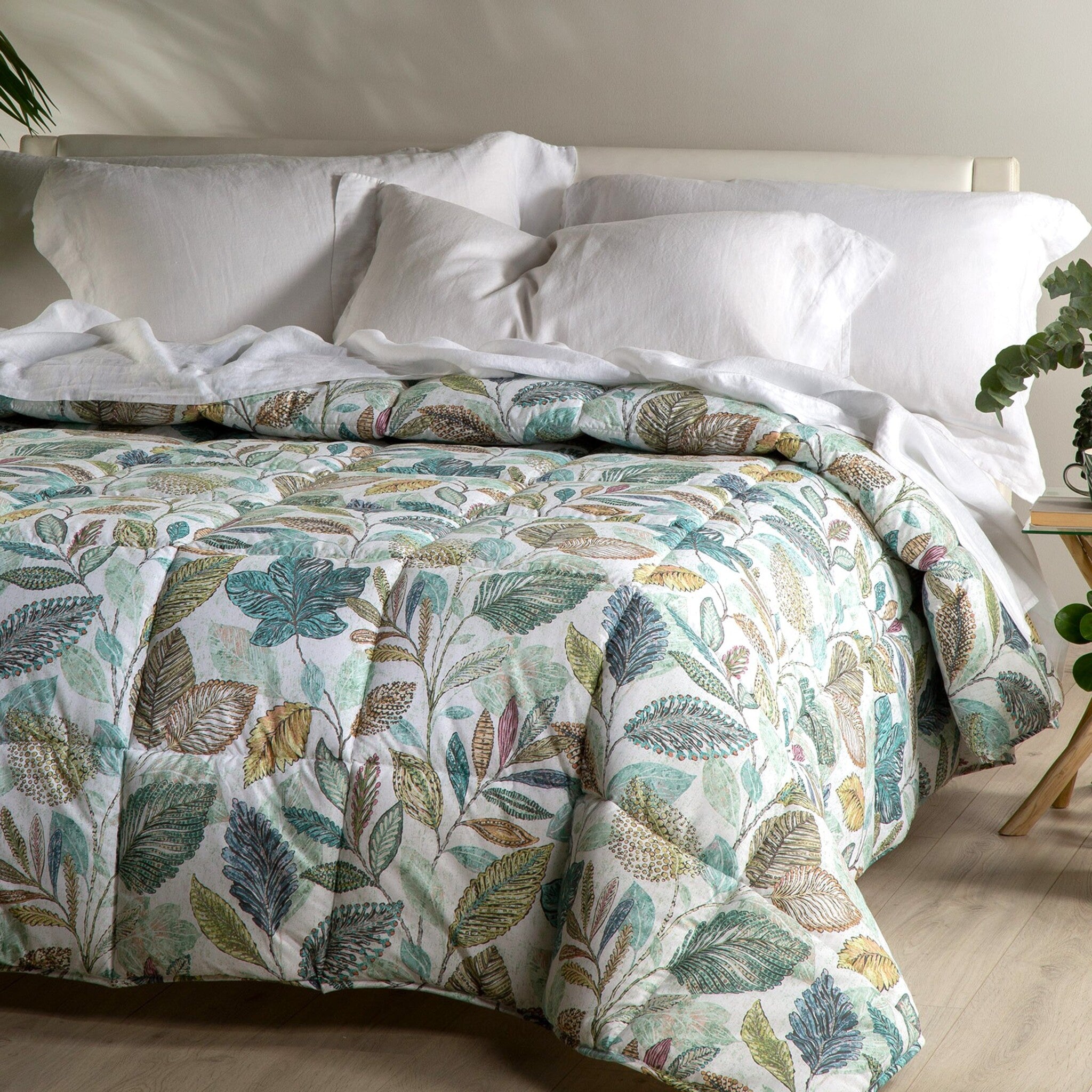 Trapunta invernale matrimoniale Caleffi Botanical sul letto, con foglie verdi, turchesi e ocra su fondo chiaro