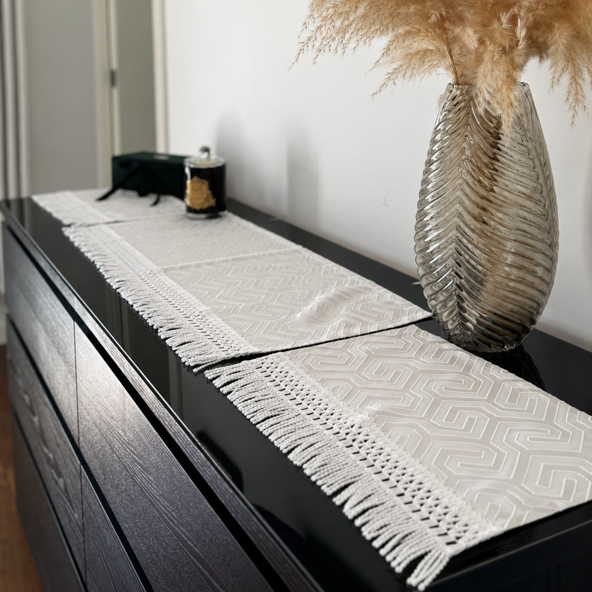 tris di centri avorio in raso jacquard con frange decorative su credenza elegante