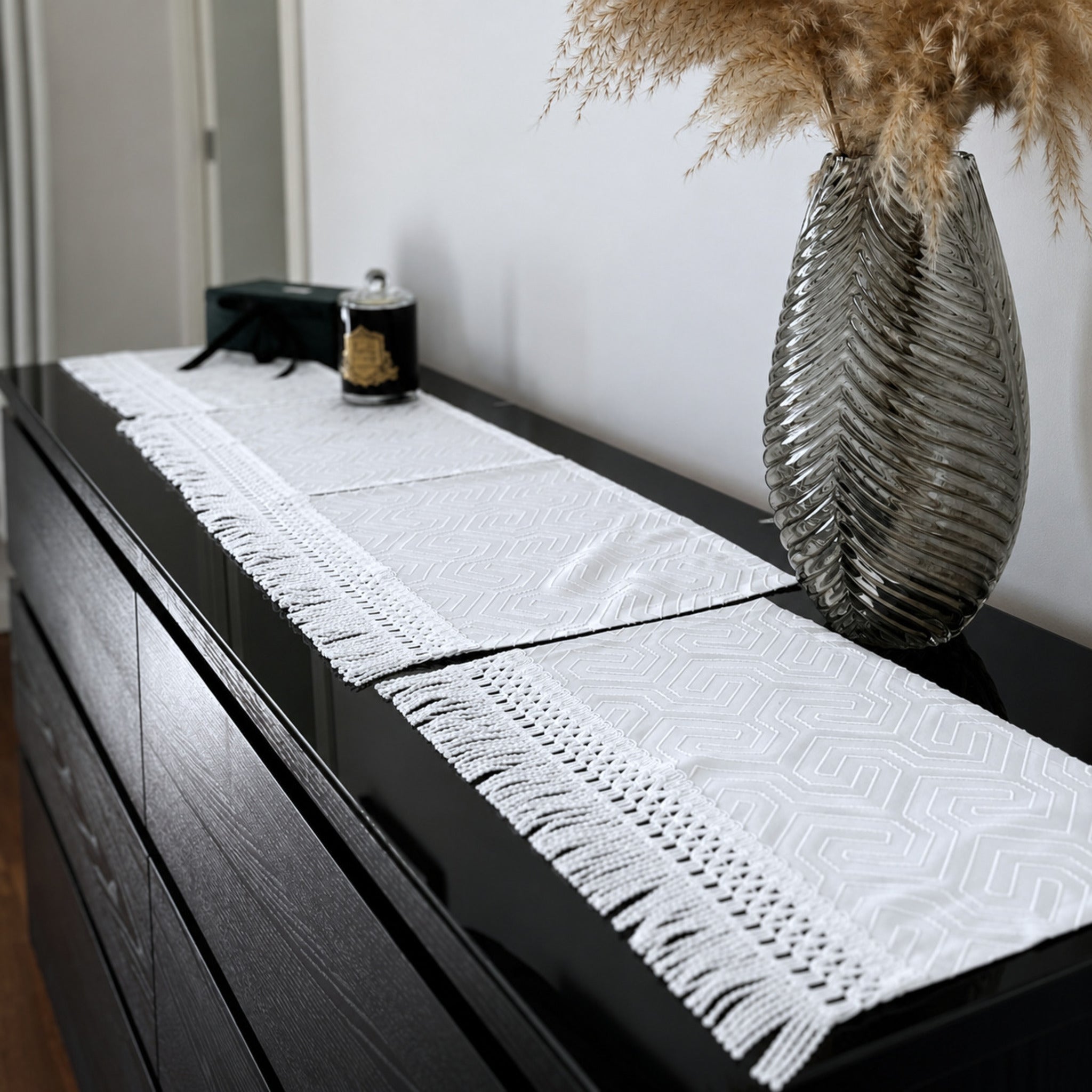 tris di centri bianco in raso jacquard con frange decorative su credenza elegante