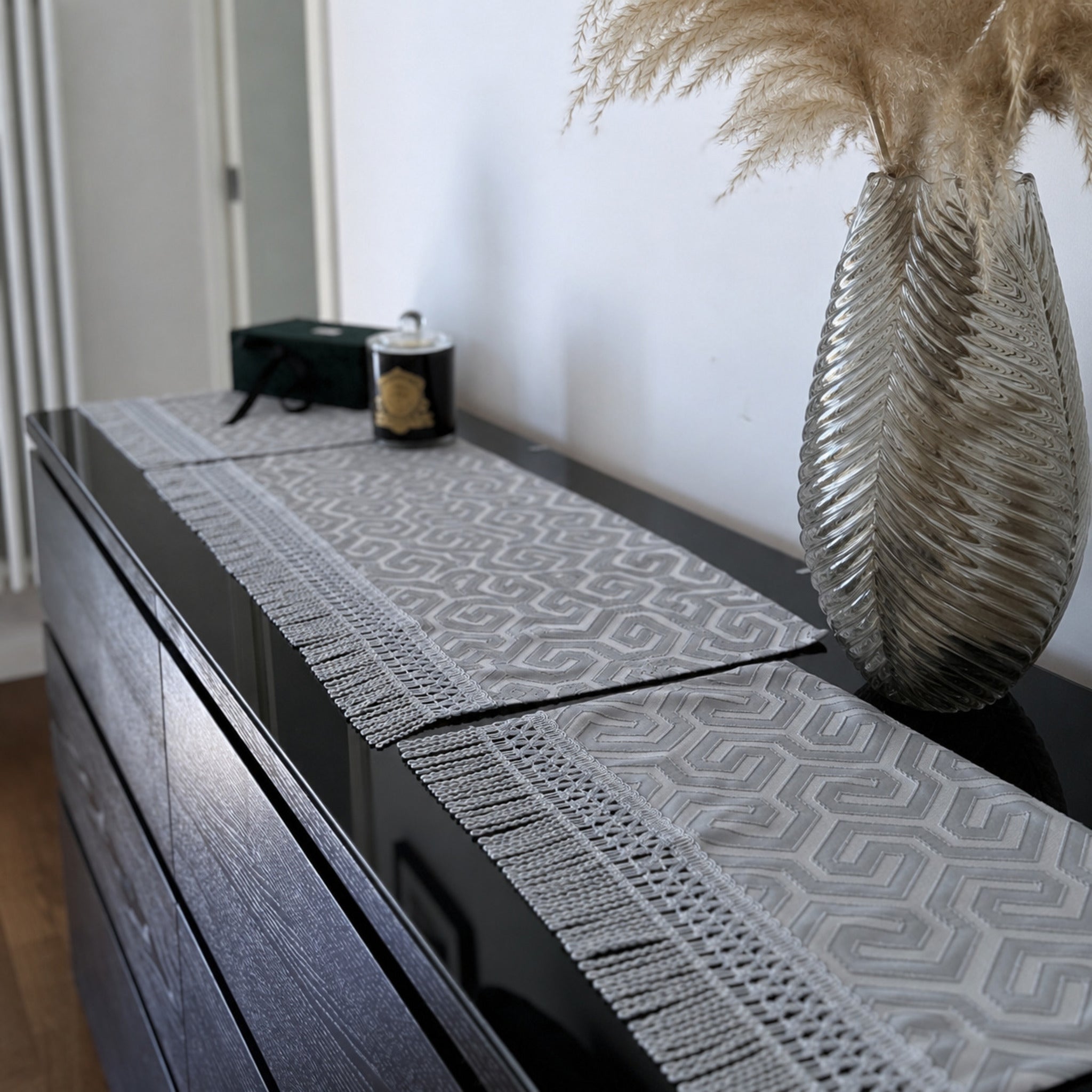 tris di centri grigio in raso jacquard con frange decorative su credenza elegante