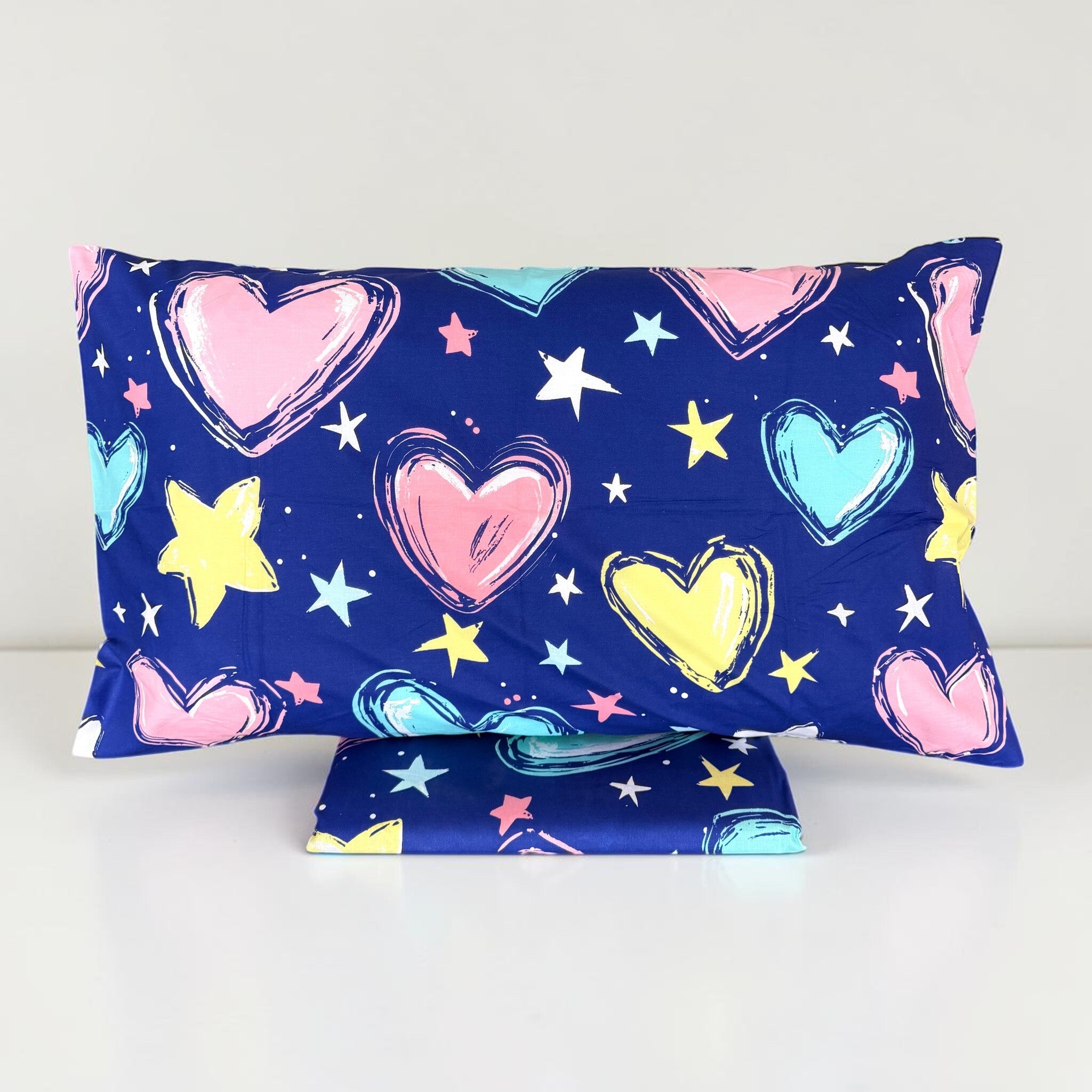 Federa Zambaiti Young 2113 con cuori colorati dai contorni a pennellata e stelle su fondo blu, con sacco copripiumino piegato sotto.